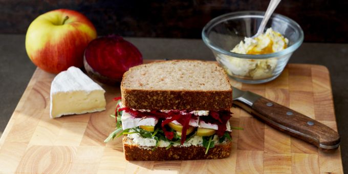 Das Frühlingssandwich punktet mit mehreren Geschmacksetagen aus Frischkäse, Rucola, Apfelschnittchen, Camembert und knackigen Randen zwischen zwei Scheiben Kartoffelbrot. Brett Sandwich Apfel Camembert Randen