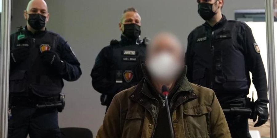 Der Angeklagte (vorne) zu Beginn des Prozesses wegen eines Dreifachmordes im Landgericht Kiel. Foto: Marcus Brandt/dpa
