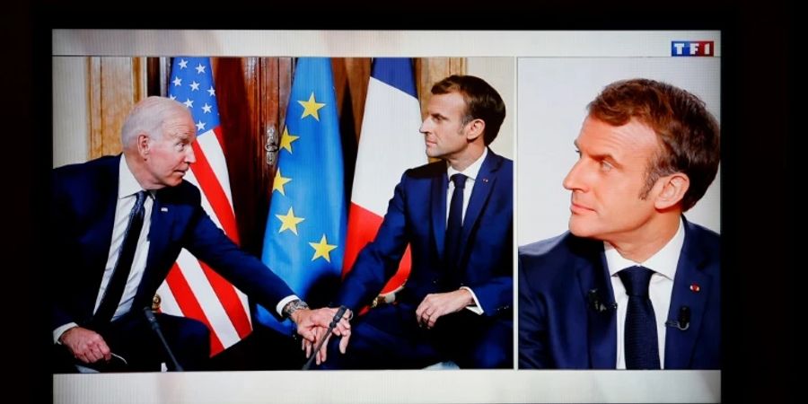 Emmanuel Macron blickt auf Foto von sich mit Joe Biden