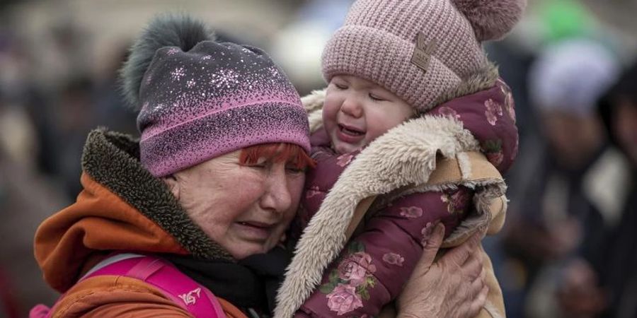 Eine weinende Frau mit einem Kind im Arm am Grenzübergang im polnischen Medyka. Foto: Visar Kryeziu/AP/dpa