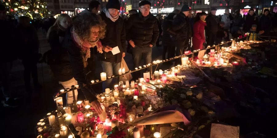 Trauernde stellen in Strassburg Kerzen auf.