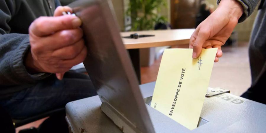 Eine Frau wirft einen Stimmzettel in eine Urne.