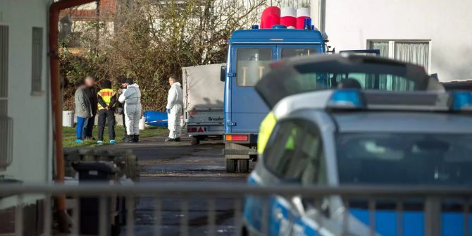 Polizisten stehen auf einem umzäunten Grundstück