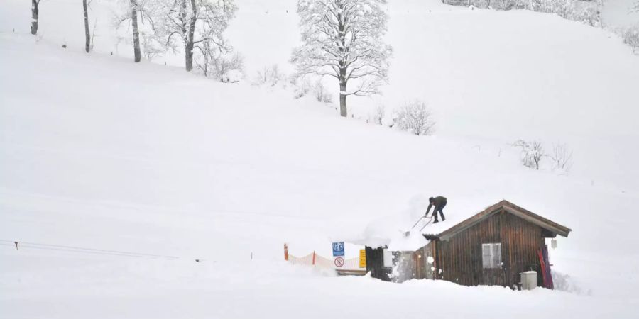 Ein Mann schaufelt Schnee vom Dach der Liftstation in Flachau (Ö).