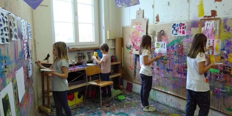 Kinder des Kinderateliers pinseln in der bunten Mal-Ecke drauflos