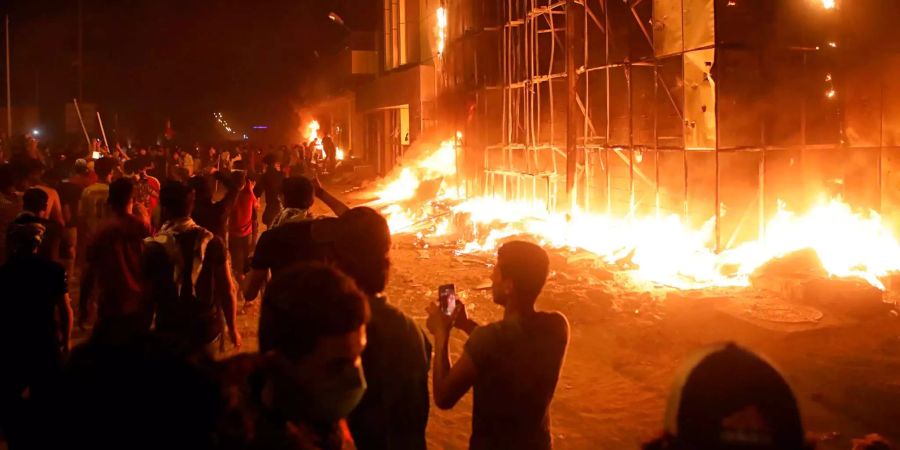 Demonstranten stehen vor einem brennenden lokalen Parteibüro in Basra.