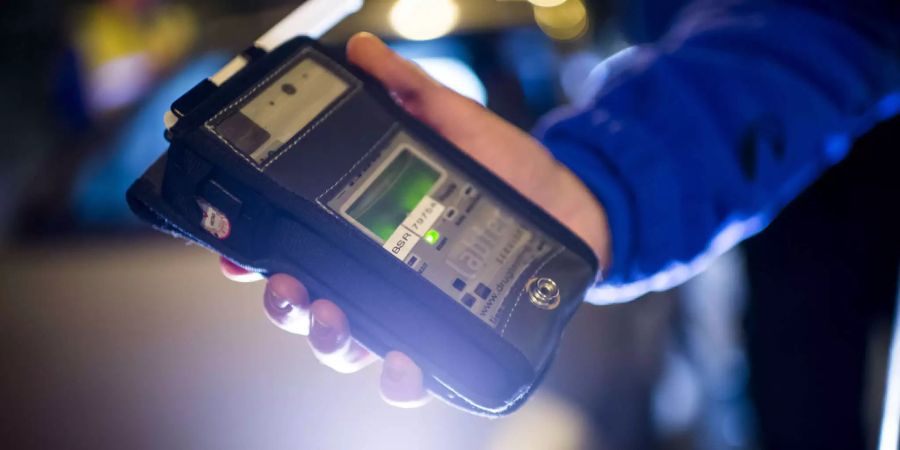Alkoholmessgerät in der Hand eines Polizisten - Keystone
