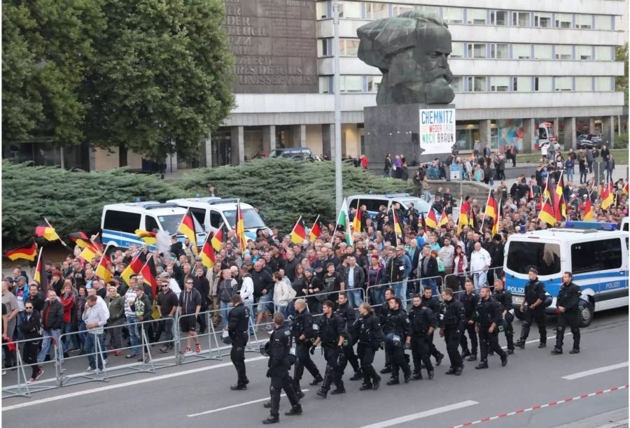 Teilnehmer einer Demonstration der rechtspopulistischen Bewegung Pro Chemnitz ziehen durch die Stadt und werden von Einsatzkräften der Polizei begleitet.