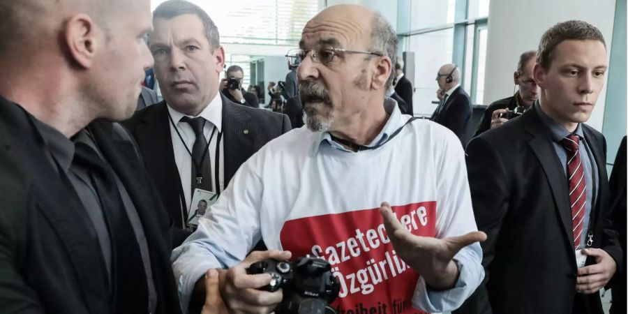 Adil Yigit, Chefredakteur des internetportals Aurupa Postasi, wird im Bundeskanzleramt aus der gemeinsamen Pressekonferenz von Bundeskanzlerin Merkel und Erdogan, Präsident der Türkei geführt. Er trägt dabei ein T-Shirt mit der Aufschrift "Pressefreiheit für Journalisten in der Türkei" und auf Türkisch "Freiheit für die Journalisten".