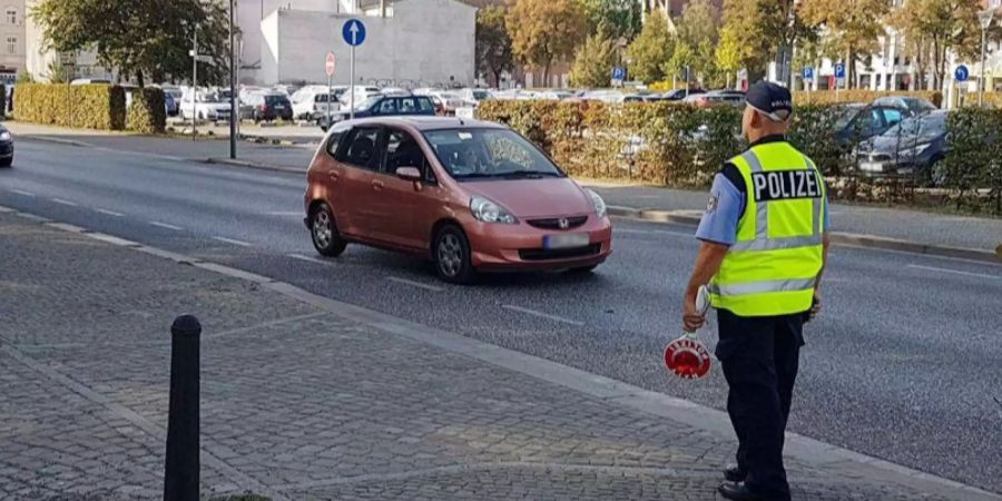 Ein deutscher Polizeibeamter kontrolliert ein Auto. (Symbolbild)