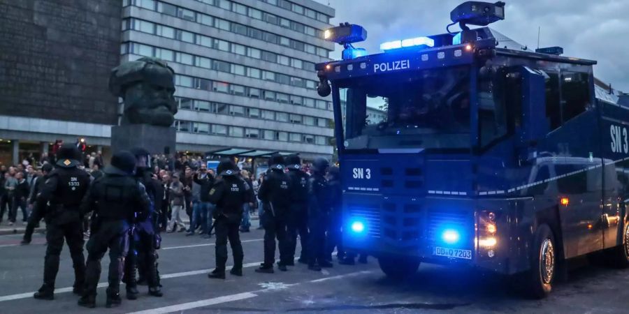 Polizisten sichern mit einem Wasserwerfer eine Demonstration der rechten Szene vor dem Karl-Marx-Denkmal.