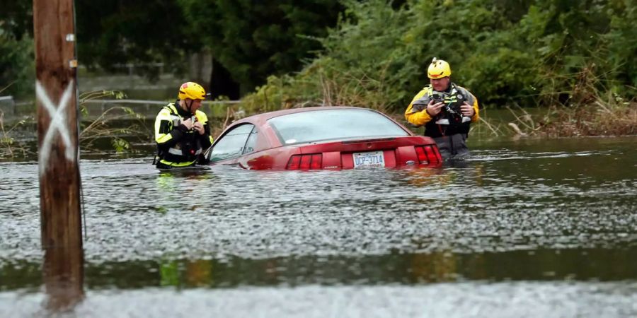 Mitglieder einer schnellen Wasserrettungsmannschaft überprüfen ein untergetauchtes Fahrzeug.