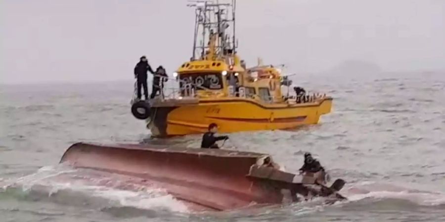 Mitglieder der koreanischen Küstenwache suchen vor der Küste nahe Incheon (Südkorea) auf einem gekenterten Fischerboot nach vermissten Insassen.