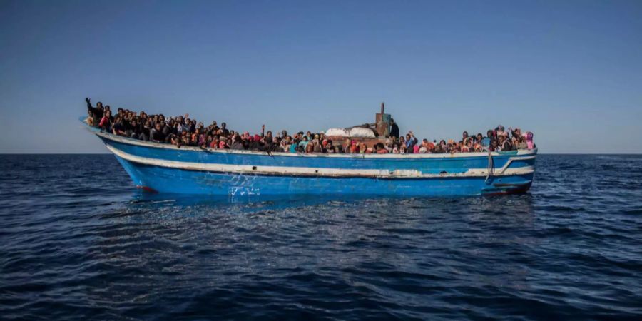 Zahlreiche Flüchtlinge auf einem Boot im Meer.