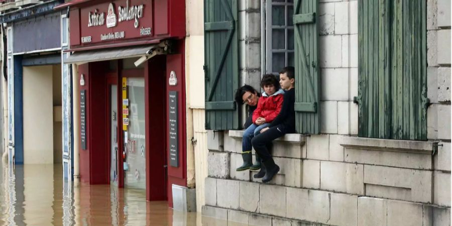 Eine Mutter und ihr Kind schauen von ihrem Haus auf den hohen Wasserstand, ausgelöst durch heftigen Regen und Stürme in Frankreich. (Symbolbild)