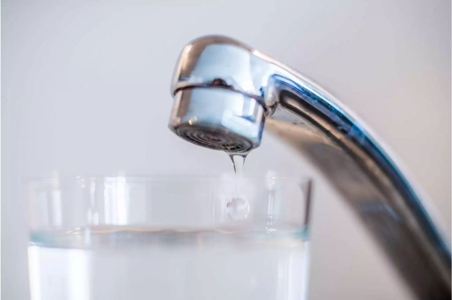 Wasserhahn lässt noch die letzten Tropfen Wasser in ein Glas fallen - Keystone