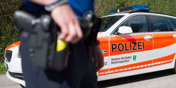 Ein Polizist der Kantonspolizei St. Gallen vor seinem Wagen. Kantonspolizei St. Gallen
