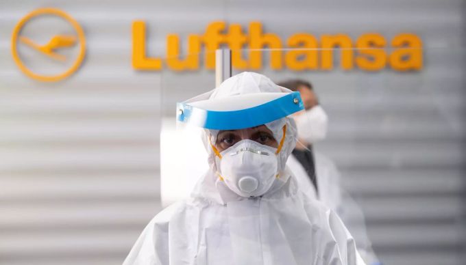 Eine Frau in Schutzkleidung steht am Flughafen München in einem Covid-19 Testcenter. Lufthansa