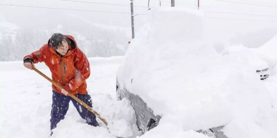 Ein Mann schaufelt sein eingeschneites Auto frei. Viele Walliser Täler sind wegen dem starken Schneefall von der Aussenwelt abgeschnitten. Foto: Andrea Soltermann/KEYSTONE/dpa