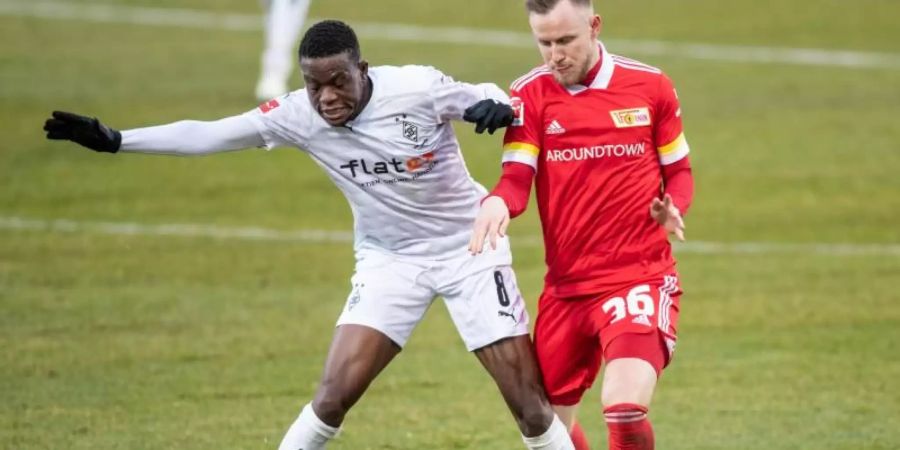 Mönchengladbachs Denis Zakaria (l) stellt seinen Körper vor Gegenspieler Cedric Teuchert um den Ball zu behaupten. Foto: Andreas Gora/dpa Pool/dpa