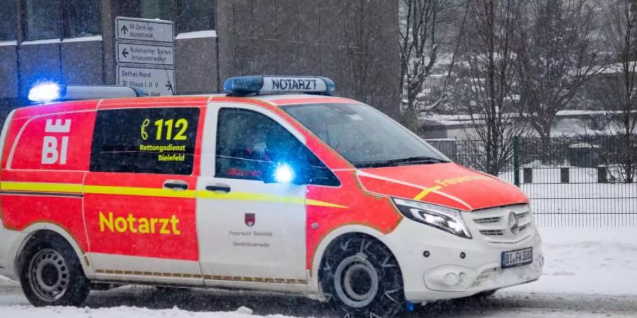 Ein Notarztwagen vom Rettungsdienst fährt mit Blaulicht auf einer zugeschneiten Strasse in Bielefeld. Foto: Friso Gentsch/dpa