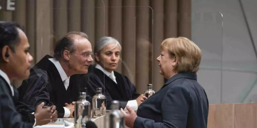 Angela Merkel (Martina Eitner-Acheampong, r), Bundeskanzlerin a.D., im Gespräch mit den Richtern in einer Szene des Justizdramas "Ökozid". Foto: Julia Terjung/rbb/zero one film/ARD/dpa