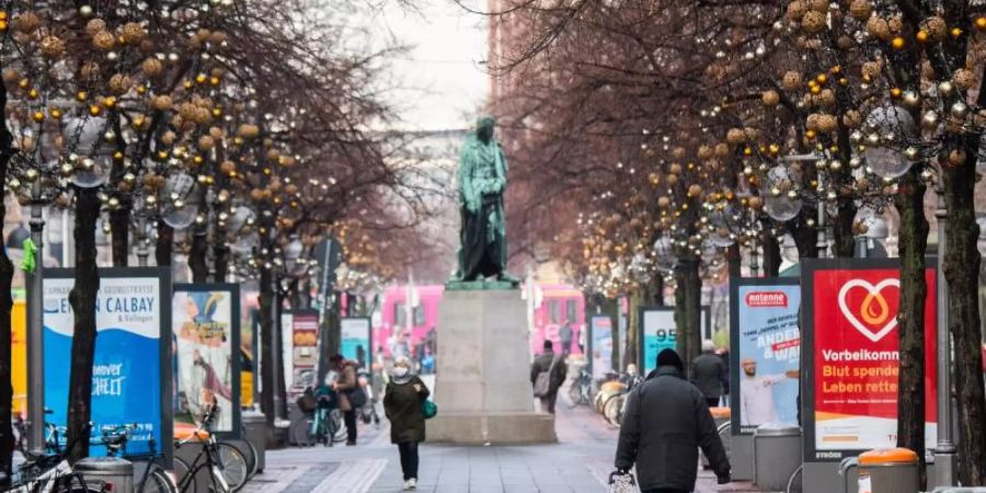 Passanten laufen durch die beinahe menschenleere Innenstadt von Hannover. Foto: Julian Stratenschulte/dpa