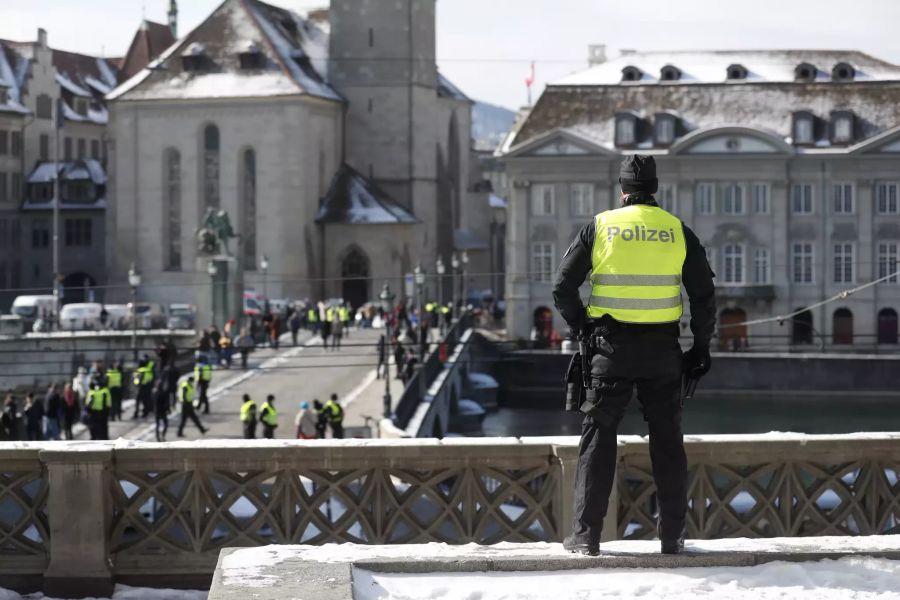 Ein Polizist schaut auf eine Brücke herab, auf der weiter Polizisten im Einsatz sind aufgrund eines stattfindenden Protestspaziergangs gegen die Corona-Massnahmen unter dem Motto «Grundrechte gelten immer».