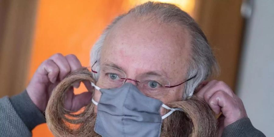 Bart-Weltmeister Jürgen Burkhardt zeigt, wie er seine Schutzmaske aufsetzt. Foto: Marijan Murat/dpa