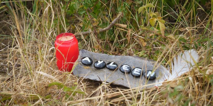 Eine Kerze und eine Tafel mit dem Namen Ayleen liegt am Ufer des Teufelsee im hessischen Wetteraukreis, wo die Leiche der 14-jährigen Ayleen gefunden wurde.