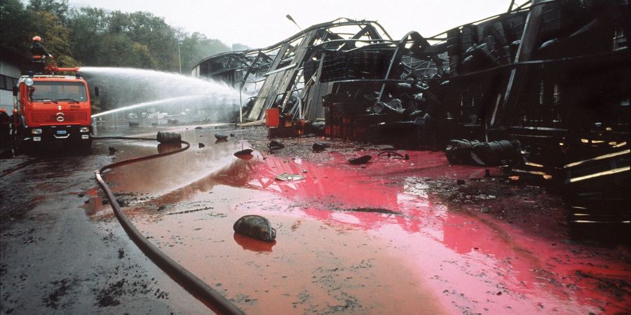 Mit einem Wasserwerfer löscht die Feuerwehr einen Brand in einem Chemiewerk des Schweizer Chemieunternehmens Sandoz, der am Tag zuvor ausgebrochen war. Das rote giftige Löschwasser gelangte in den Rhein.