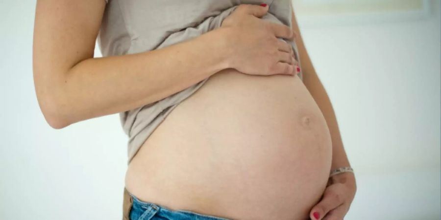 Eine Frau hält ihren Babybauch