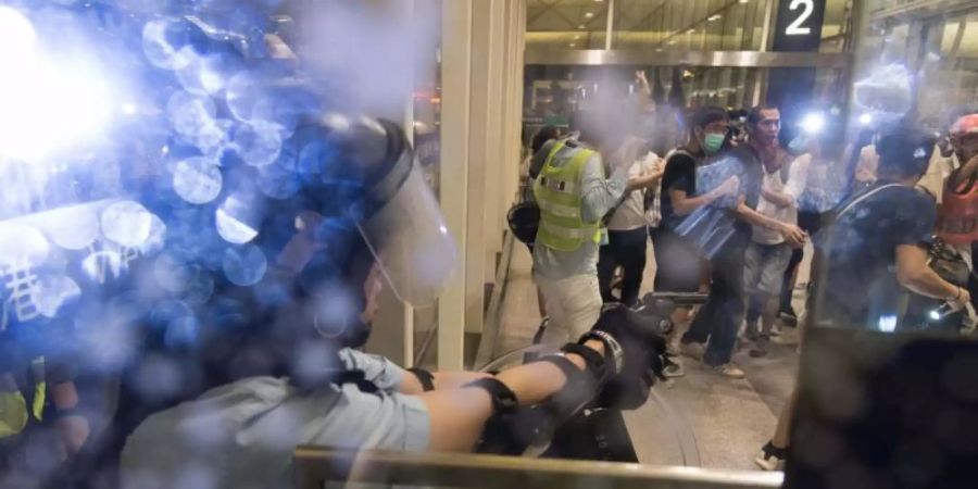 Ein Polizist richtet im Flughafen von Hongkong seine Waffe auf Demonstranten. Tausende Bewohner der Stadt hatten ihre Proteste gegen die Stadtregierung und gegen die Polizeigewalt in den vergangenen Tagen auf den Flughafen ausgeweitet. Foto: Aidan Marzo/SOPA Images via ZUMA Wire