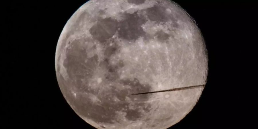 Ein Flugzeug fliegt am Abend am Vollmond vorbei. Foto: Robert Michael