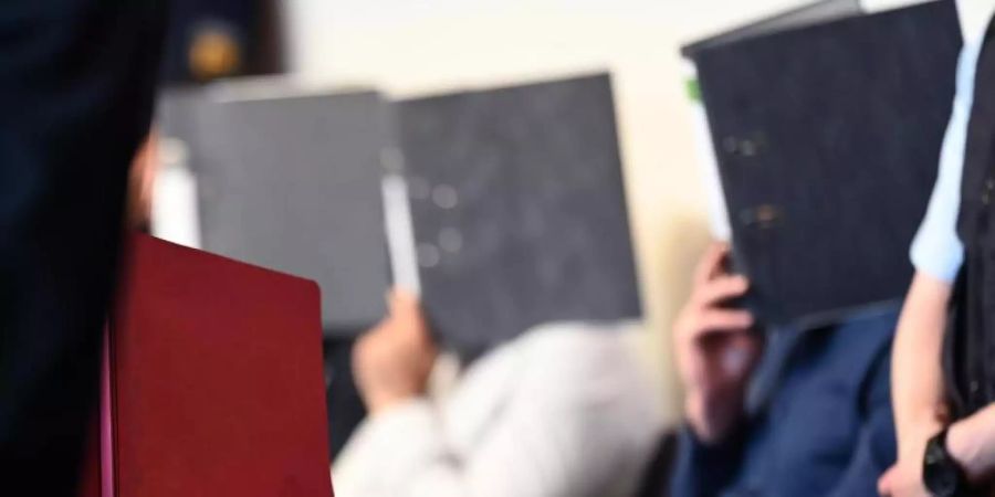 Angeklagte sitzen vor dem Prozessbeginn im Gerichtssaal in Freiburg. Foto: Patrick Seeger