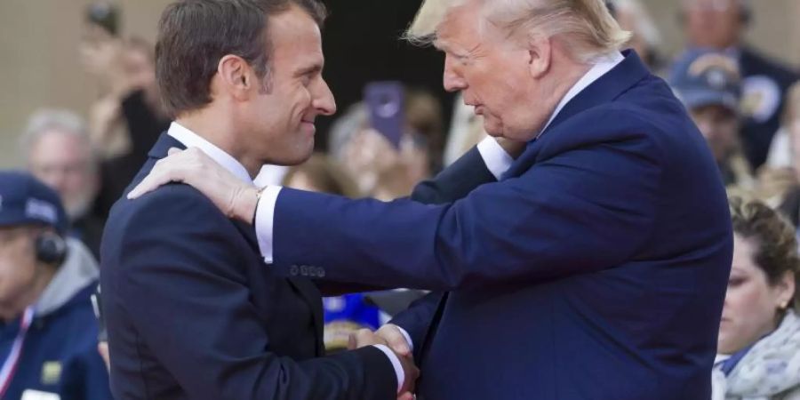 Emmanuel Macron schüttelt am Rande der D-Day-Gedenkfeiern die Hand von Donald Trump. Foto: Alex Brandon/AP