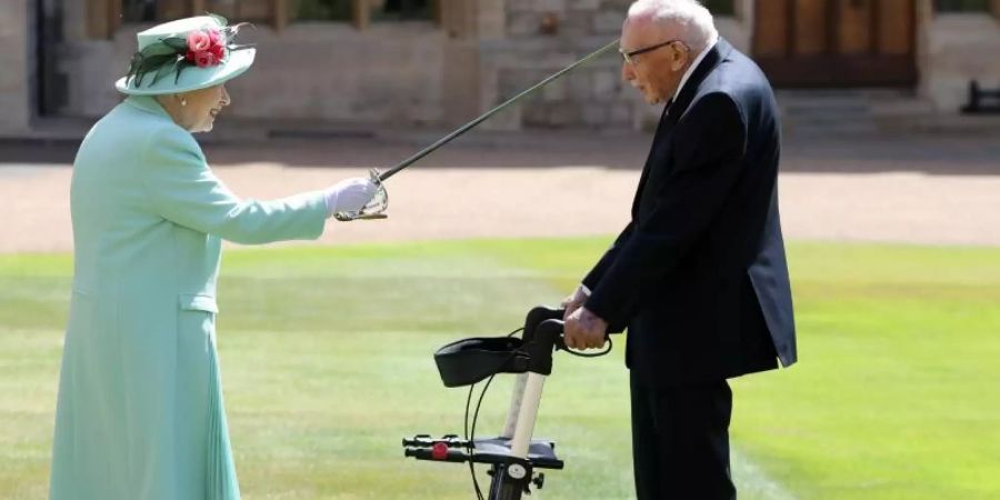 Königin Elizabeth II. (l) schlägt Tom Moore während einer Zeremonie im Freien auf Schloss Windsor zum Ritter. Foto: Chris Jackson/PA Wire/dpa