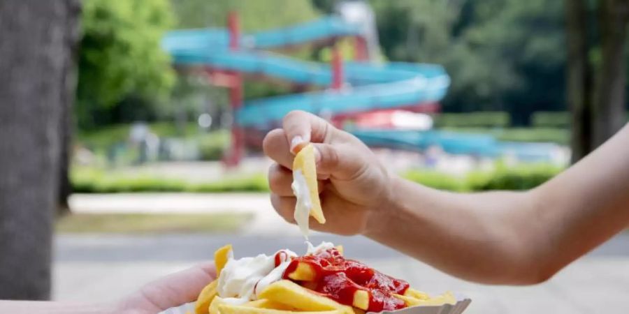 Für viele Besucher gehört eine Schale Pommes rot-weiss zum Freibadbesuch einfach dazu. Foto: Christoph Soeder/dpa
