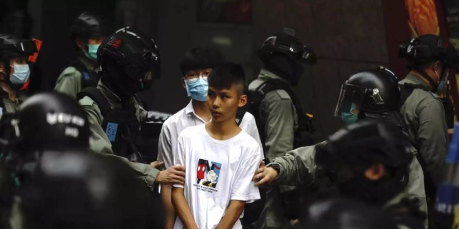 Bereitschaftspolizisten halten im Zentrum von Hongkong zwei junge Demonstranten fest. Foto: Kin Cheung/AP/dpa