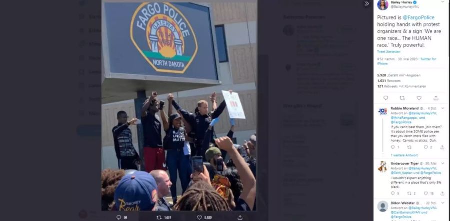 Ein Polizist in North Dakota hält die Hände von Demonstranten und ein Schild in die Höhe. Auf dem Schild steht geschrieben: «Wir sind eine Rasse, die Menschheit!»