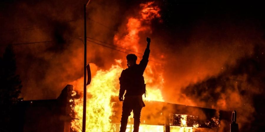 Demonstrant vor brennendem Gebäude.