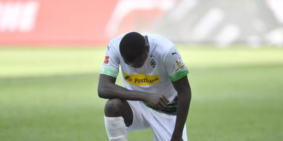 Mönchengladbachs Marcus Thuram kniet nach seinem ersten Treffer der Partie auf dem Rasen. Foto: Martin Meissner/AP Pool/dpa