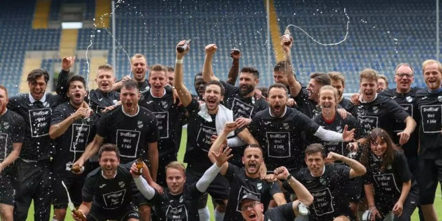 Verls Spieler feiern den Aufstieg in die 3. Liga. Foto: Friso Gentsch/dpa
