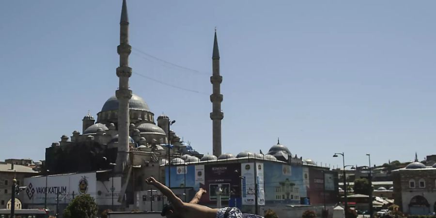 Vor dem Hintergrund der historischen Neuen Moschee springt ein Jugendlicher von der Galata Brücke in den Bosporus. Foto: Emrah Gurel/AP/dpa