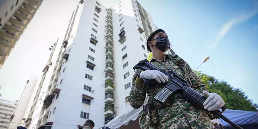 Bewaffnete Soldaten stehen Wache vor dem Wohngebiet Pangsapuri Permai, das aufgrund eines drastischen Anstiegs der Corona-Infektionen unter strenger Bewachung steht. Foto: Vincent Thian/AP/dpa