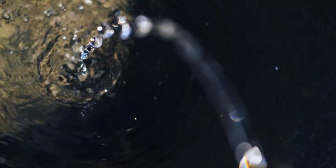 Ein Wasserstrahl plätschert in einen Brunnen.
