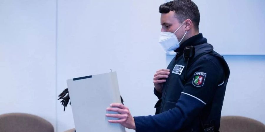 Der Angeklagte wird in Handschellen in einen Gerichtssaal im Landgericht Köln geführt. Foto: Rolf Vennenbernd/dpa