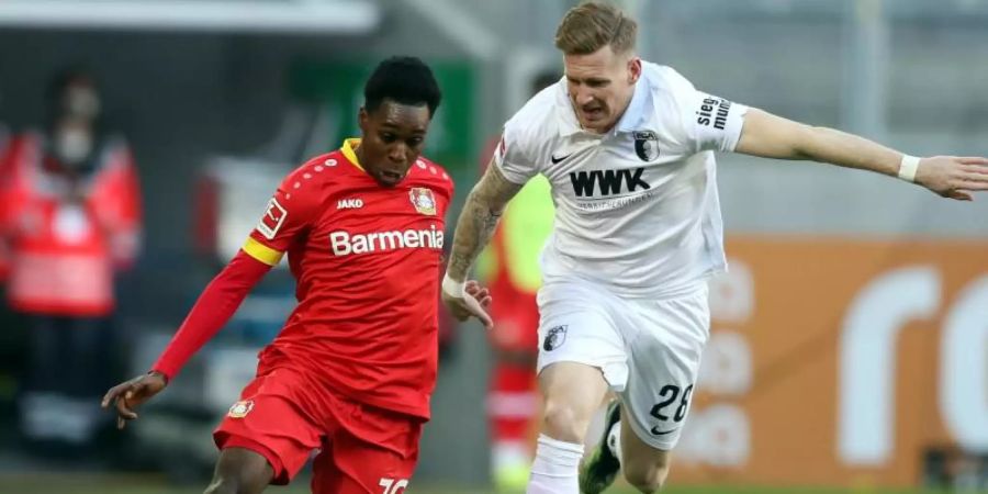 Leverkusens Jeremie Frimpong (l) und Augsburgs Andre Hahn im Zweikampf um den Ball. Foto: Tom Weller/dpa