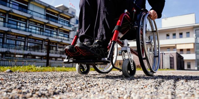 Nicht gerade optimal - ein Rollstuhlfahrer fährt über einen Kiesweg. Nicht gerade optimal - ein Rollstuhlfahrer fährt über einen Kiesweg.