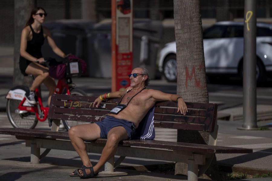 Ein Mann in Barcelona, Spanien, sitzt bei der Hitze oben ohne auf einer Parkbank.